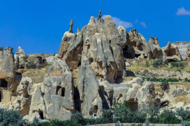 Türkiye 'nin Kapadokya kentinin yakınlarındaki göz kamaştırıcı renkli vadilerin önündeki taş evlerle Greme' e fantastik bir manzara