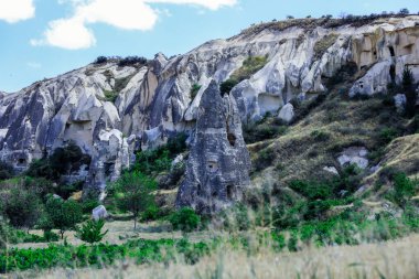 Türkiye 'nin Kapadokya kentinin yakınlarındaki göz kamaştırıcı renkli vadilerin önündeki taş evlerle Greme' e fantastik bir manzara