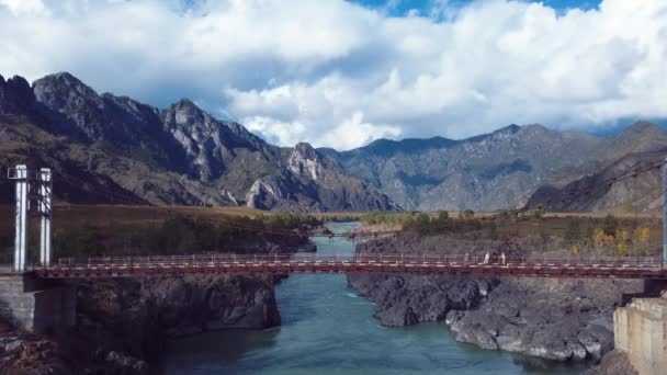 4K空撮ロシア アルタイ山脈の化学工法によるオロコトイ集落近くのカトゥン川にかかる秋の風景と橋のビデオ — ストック動画