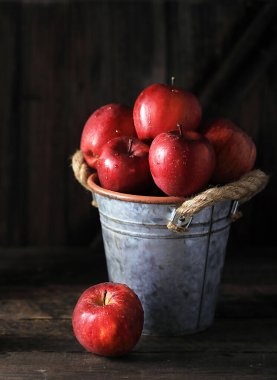 Ahşap bir masada kırmızı elmalarla dolu bir hayat.