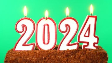 2024 numaralı pastada yanan mum. Yeni yıl teması ve yılbaşı krom anahtarı. Yeşil Ekran.