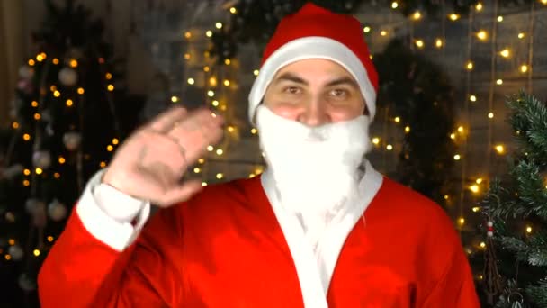 Санта Клаус машет рукой в удивительном интерьере дома, глядя в камеру. Счастливого Рождества! — стоковое видео