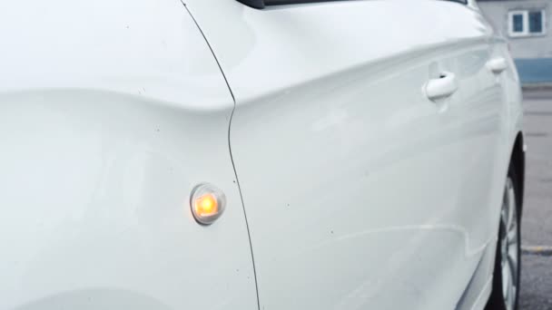 Detalle del coche. Señal de giro naranja lateral parpadea en el guardabarros de un coche blanco. Primer plano.. — Vídeos de Stock