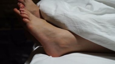 Battaniyenin altında dinlenen çiftler. Yataklarındaki battaniyenin altında uyuyan kadın ve erkeğin güzel ayakları