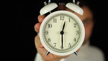 12: 30 'da. 12: 30 kilidini gösteren ve çalan alarm saatini tutan insan eli..