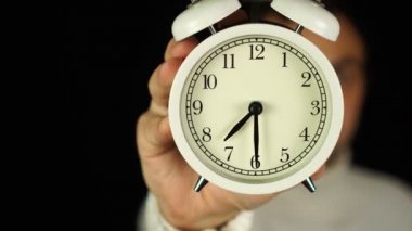 7: 30 'da. 7: 30 kilidini gösteren ve çalan alarm saatini tutan insan eli..