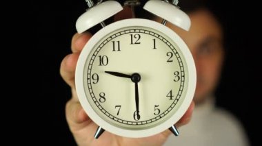 9: 30 kilidi. 9: 30 kilidini gösteren ve çalan alarm saatini tutan insan eli..
