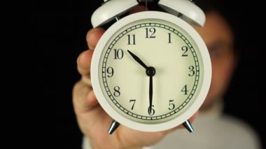 Saat 10: 30 'da. 10: 30 kilidini gösteren ve çalan alarm saatini tutan insan eli..
