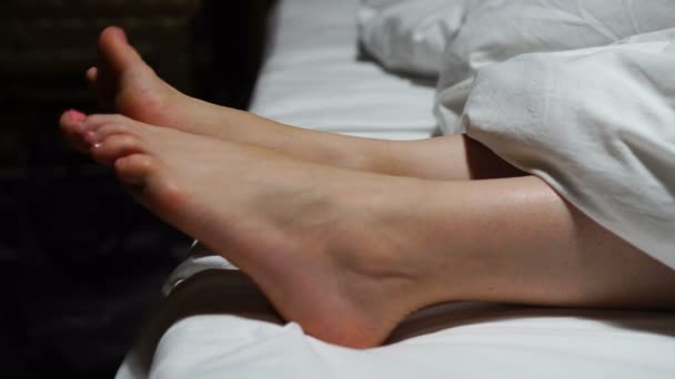 Kobiety stopy wystające z koca na łóżku w domu — Wideo stockowe