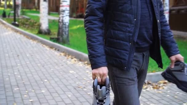 Nepoznatelný muž nosí v rukou boty. — Stock video