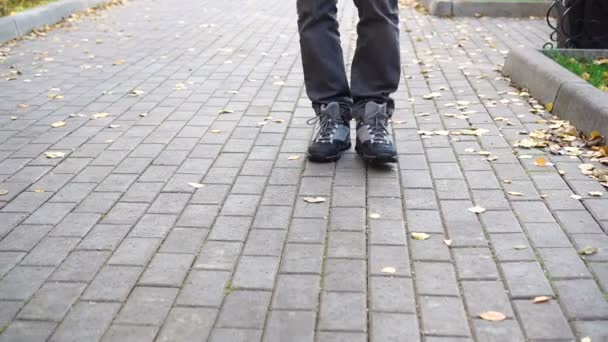 Mans footsteps on dlažba covered with fallen leaves — Stock video