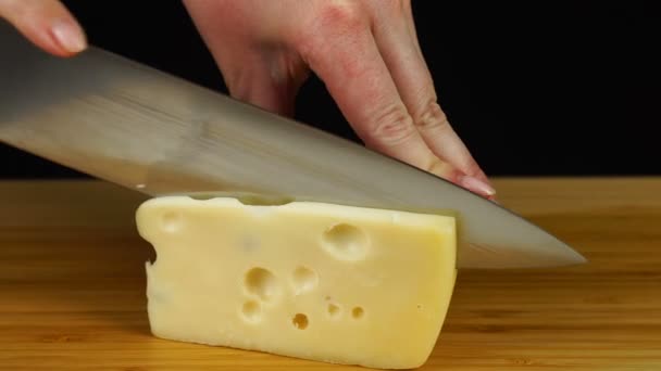 Mains féminines coupant le fromage avec un couteau sur une planche à découper en bois — Video