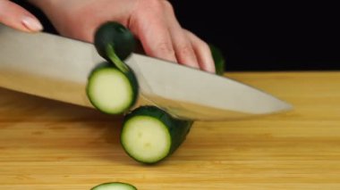 Bıçak salatalığı keser. Tahta kesme tahtasında sebze dilimlemek..