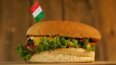 Üstünde küçük Macar bayrağı olan leziz bir hamburger ve kürdan. Lezzetli hamburger dönüyor..