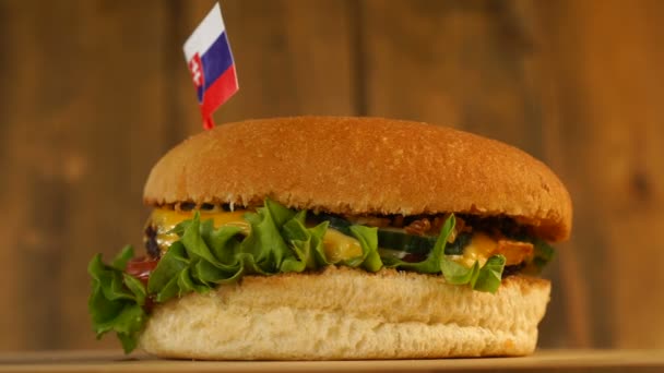 Burger lezat dengan bendera Slowakia kecil di atasnya dengan tusuk gigi. Hamburger Yummy berputar. — Stok Video