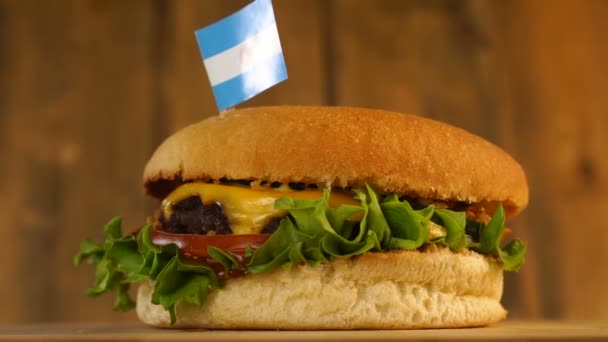 Delicious burger with small Argentinian flag on top of them with toothpicks. Yummy hamburger rotating. — Stock Video