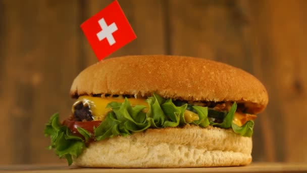 Köstlicher Burger mit kleiner Schweizer Flagge darüber mit Zahnstochern. Leckere Hamburger rotieren. — Stockvideo