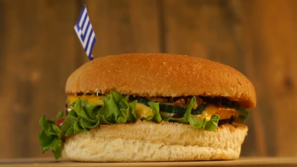 Deliciosa hamburguesa con bandera griega pequeña encima de ellos con palillos de dientes. Deliciosa hamburguesa giratoria. — Vídeo de stock