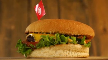 Üstünde küçük Tunus bayrağı olan leziz bir burger ve kürdan. Lezzetli hamburger dönüyor..