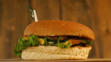 Üstünde küçük Pakistan bayrağı olan leziz bir hamburger ve kürdan. Lezzetli hamburger dönüyor..