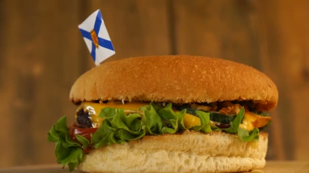 Köstlicher Burger mit einer kleinen Fahne von Nova Scotia darüber mit Zahnstochern. Leckere Hamburger rotieren. — Stockvideo