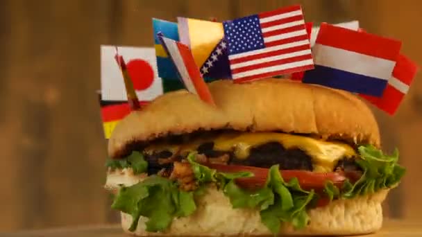 Hamburguesa fresca con bandera pequeña de muchos países encima con palillos de dientes. — Vídeo de stock