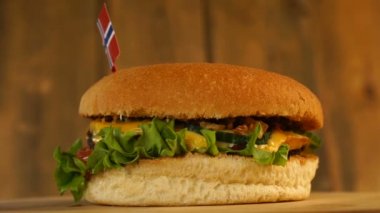 Üstünde küçük Norveç bayrağı olan leziz bir burger ve kürdan. Lezzetli hamburger dönüyor..