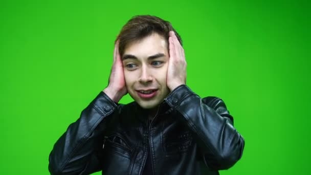 Bílý muž v kožené bundě drží hlavu v panice nebo stresu nad zeleným pozadí obrazovky. — Stock video