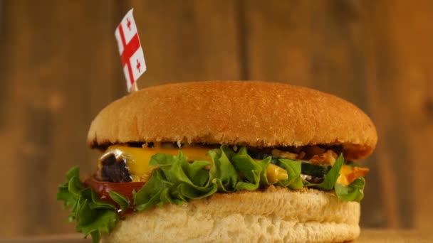 Delicioso hambúrguer com pequena bandeira georgiana em cima deles com palitos. Hambúrguer delicioso rotativo. — Vídeo de Stock