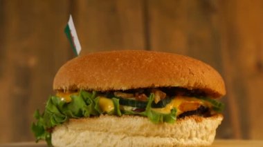 Üstünde kürdanla Cezayir bayrağı olan lezzetli bir burger. Lezzetli hamburger dönüyor..