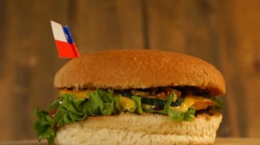 Üstünde kürdanla küçük Şili bayrağı olan lezzetli bir burger. Lezzetli hamburger dönüyor..