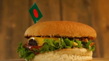 Üstünde kürdanla küçük Bangladeş bayrağı olan leziz bir burger. Lezzetli hamburger dönüyor..