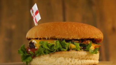 Üstünde kürdanla Kuzey İrlanda bayrağı olan lezzetli bir burger. Lezzetli hamburger dönüyor..
