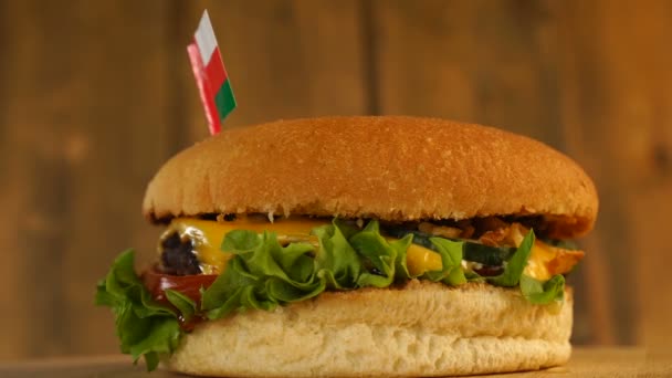 Köstlicher Burger mit einer kleinen omanischen Flagge darüber mit Zahnstochern. Leckere Hamburger rotieren. — Stockvideo