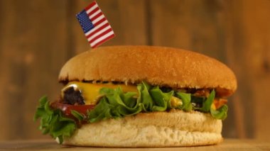 Üstünde kürdanla küçük Amerikan bayrağı olan leziz bir burger. Lezzetli hamburger dönüyor..