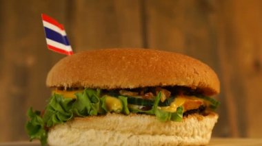 Üstünde kürdanla küçük Tayland bayrağı olan lezzetli bir burger. Lezzetli hamburger dönüyor..