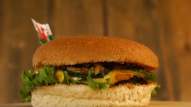 Üstünde kürdanla küçük Galler bayrağı olan leziz bir burger. Lezzetli hamburger dönüyor..