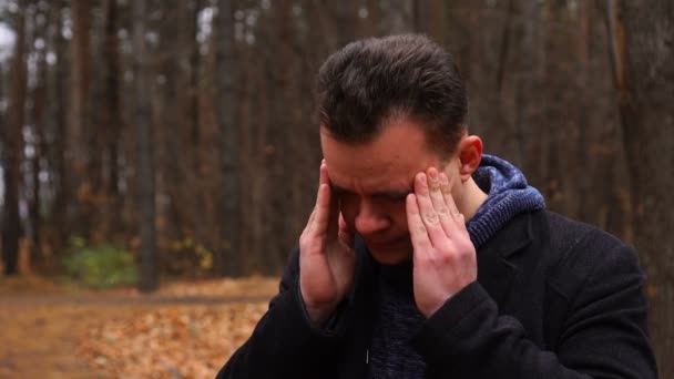 Hombre preocupado, estresado o con dolor de cabeza en el parque de otoño — Vídeo de stock