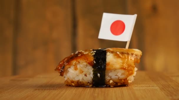 Balık, pirinç, deniz yosunu ve üzerinde küçük Japon bayrağı olan suşi tahta bir döner tablada döner.. — Stok video