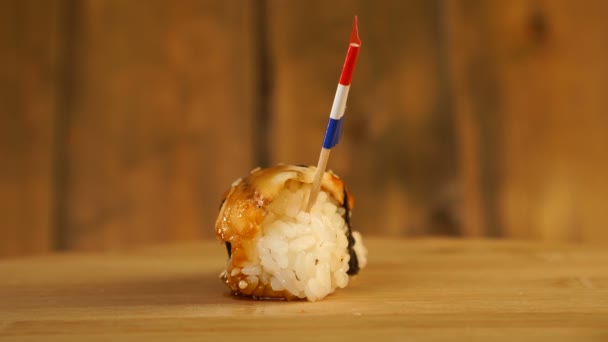 Sushi con pescado, arroz, algas marinas y pequeña bandera de Croacia en la parte superior rotar en un tocadiscos de madera. — Vídeos de Stock
