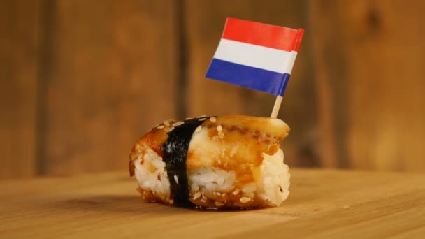 Sushi mit Fisch, Reis, Algen und einer kleinen Flagge der Niederlande auf einem hölzernen Drehteller. — Stockvideo