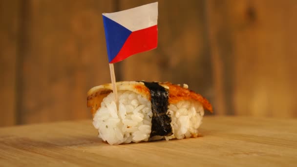 Sushi com peixe, arroz, algas marinhas e pequena bandeira da República Checa em cima giram em uma plataforma giratória de madeira. — Vídeo de Stock