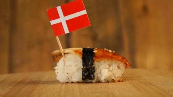 Sushi with fish, rice, seaweed and small flag of Denmark on top rotate on a wooden turntable. — Stock Video