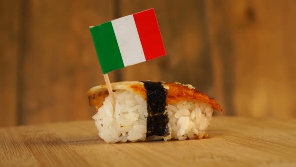 Sushi with fish, rice, seaweed and small flag of Italy on top rotate on a wooden turntable. — Stock Video