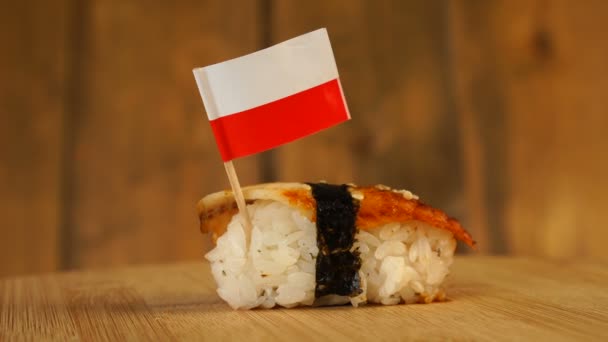 Sushi z rybą, ryżem, wodorostami i małą flagą Polski na wierzchu obracają się na drewnianym gramofonie. — Wideo stockowe