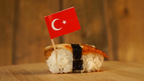 Sushi with fish, rice, seaweed and small flag of Turkey on top rotate on a wooden turntable. — Stock Video