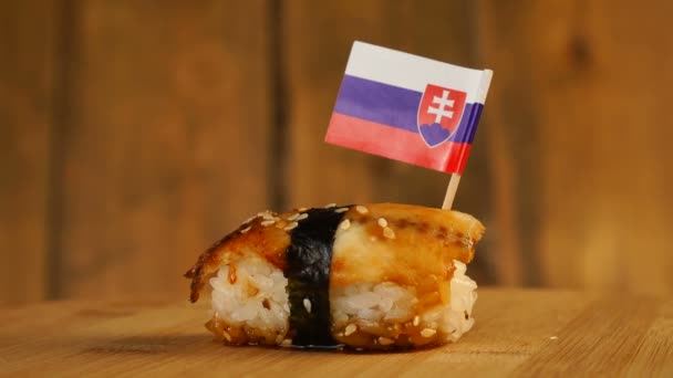 Sushi med fisk, ris, tång och liten flagga Slovakien på toppen rotera på en trä skivspelare. — Stockvideo