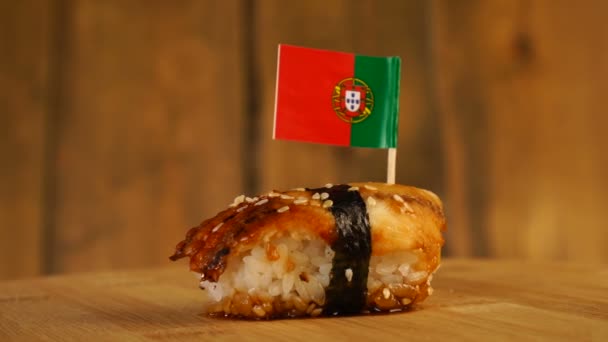 Sushi med fisk, ris, alger och liten flagga i Portugal på toppen rotera på en träskivspelare — Stockvideo
