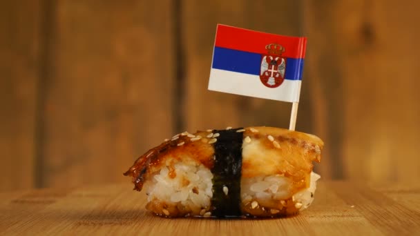 Sushi with fish, rice, seaweed and small flag of Serbia on top rotate on a wooden turntable. — Stock Video