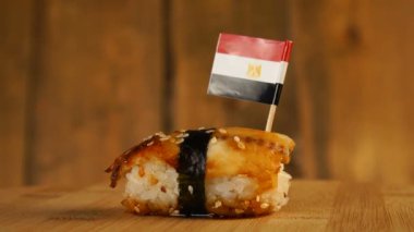 Balık, pirinç, deniz yosunu ve üzerinde küçük Mısır bayrağı olan suşi tahta bir döner döner..